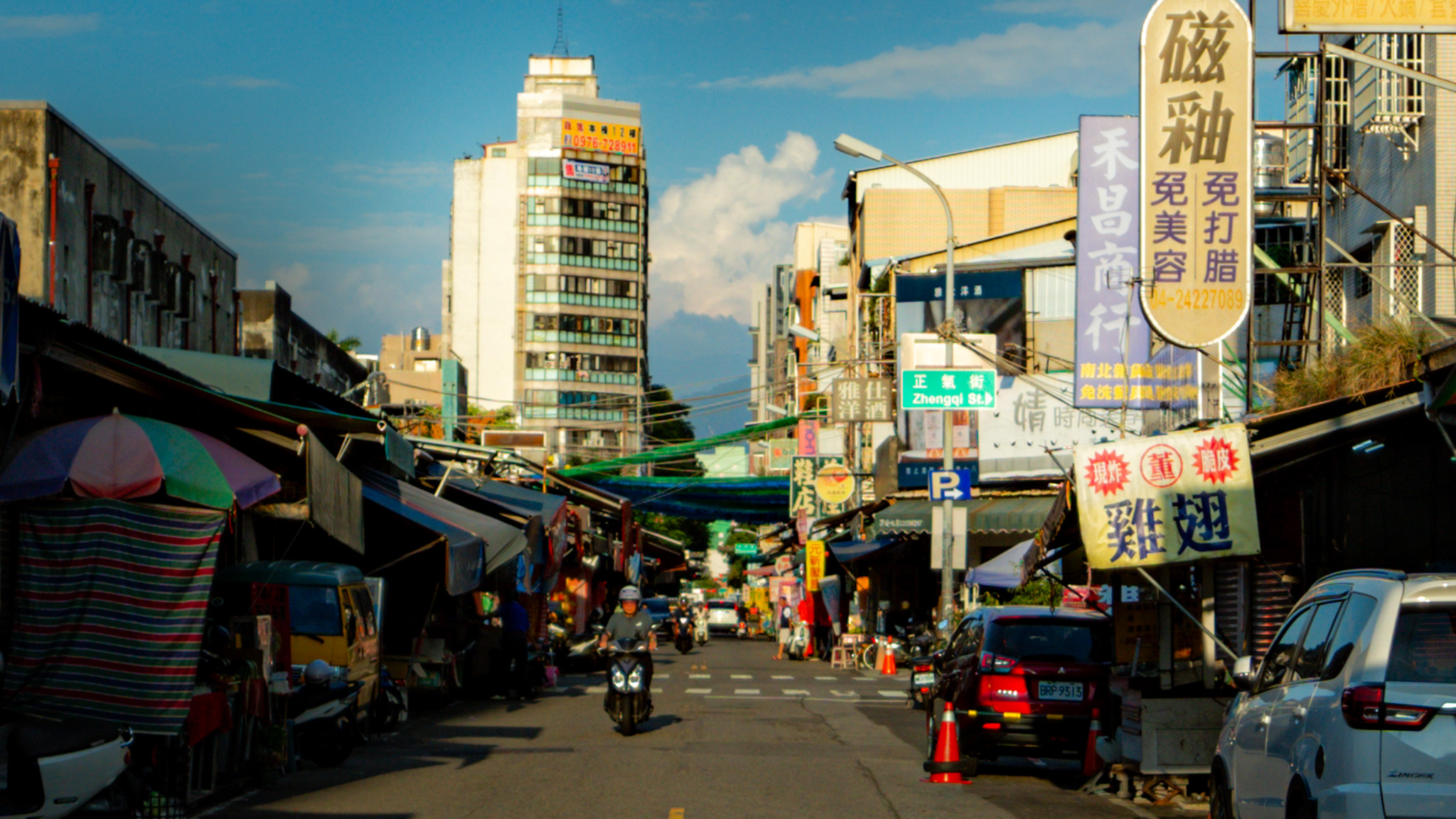 Taiwan market street with storefront signs and scooters